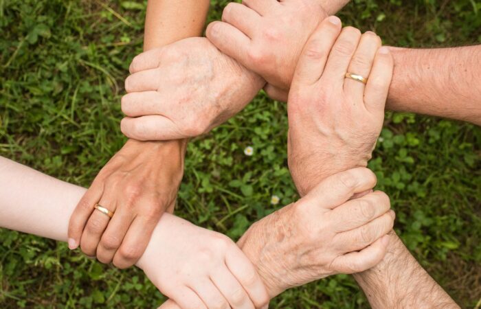 six hands holding the wrist of their neighbout to form a circle which represnts support