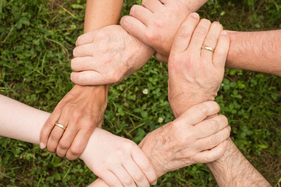 six hands holding the wrist of their neighbout to form a circle which represnts support