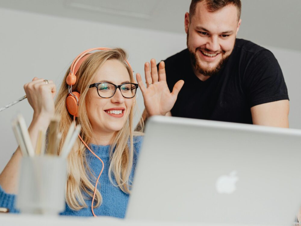 A man and a woman smiling whilst looking at their laptop