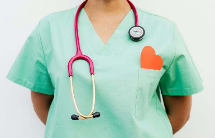 This shows a picture of a upper body in hospital scrubs with a heart shaped post it above the pocket.